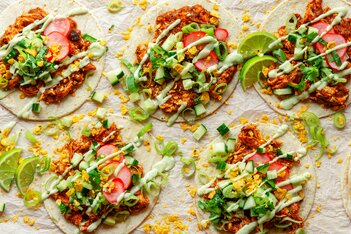 Fire fargerike tacoer toppet med kjøtt, revet ost, frisk koriander og livlige grønnsaker på flatbrød.