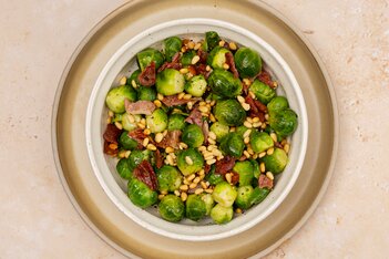 En livlig grønn salat med blandet salat, kikerter og fargerike grønnsaker servert på en rund tallerken.